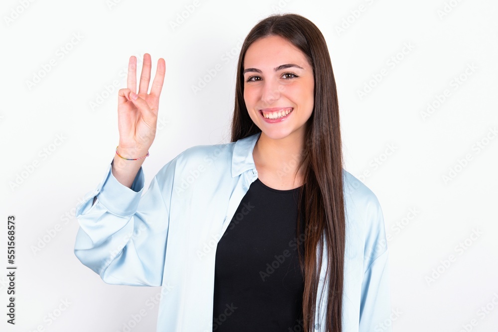 Young caucasian woman wearing blue overshirt over white background showing and pointing up with fingers number three while smiling confident and happy. Young caucasian woman wearing blue overshirt over white background showing and pointing up with fingers number three while smiling confident and happy.