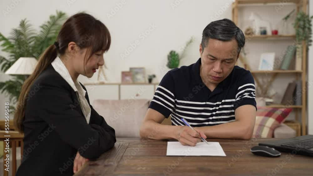 slow motion of elderly man client putting signature on his disability insurance document after consultation at home. the female agent thanks him for the trust slow motion of elderly man client putting signature on his disability insurance document after consultation at home. the female agent thanks him for the trust