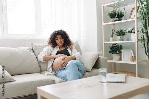 Pregnant woman headache lies at home in a shirt and jeans on the couch fatigue and heaviness in the last month of pregnancy before childbirth, motherhood difficulties, nausea © SHOTPRIME STUDIO