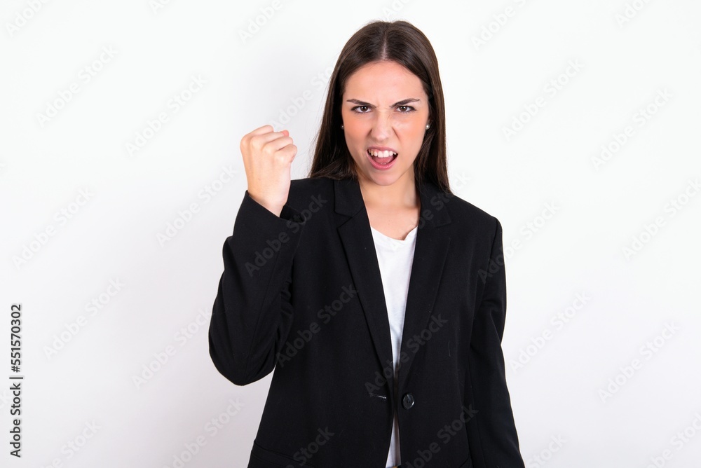 Young caucasian woman wearing jacket over white background angry and mad raising fist frustrated and furious while shouting with anger. Rage and aggressive concept. Young caucasian woman wearing jacket over white background angry and mad raising fist frustrated and furious while shouting with anger. Rage and aggressive concept.