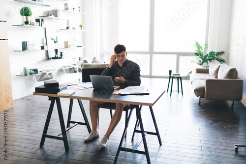 Half dressed man using earbuds while working at home office © BullRun