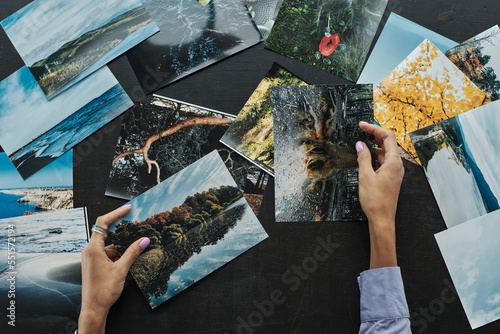 Hands of female photographer checking photos of landcapes she printed photo