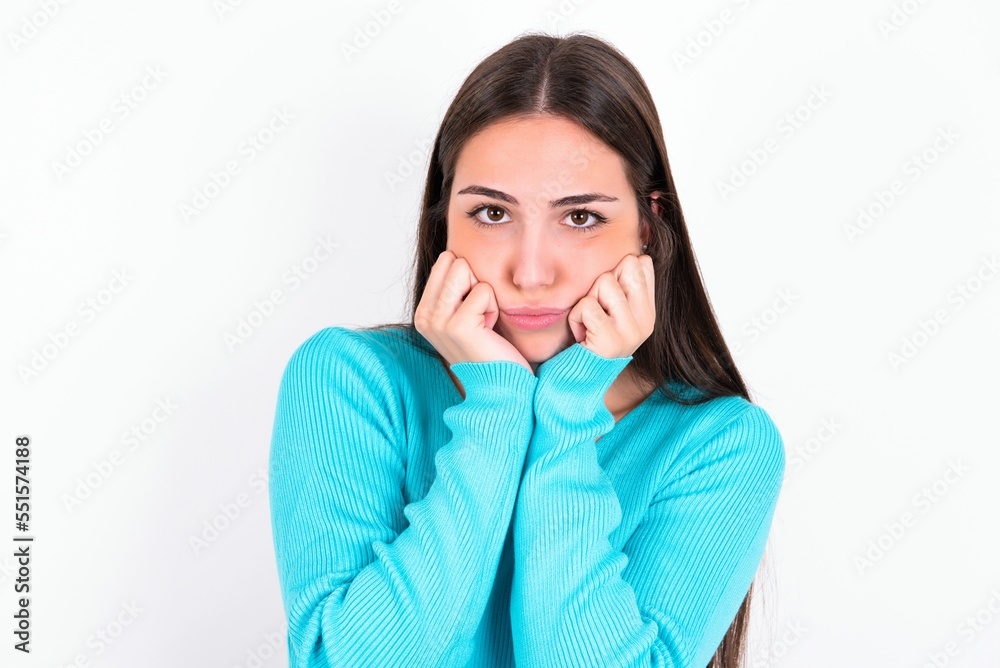 Portrait of sad Young caucasian woman wearing blue sweater over white background hands face Portrait of sad Young caucasian woman wearing blue sweater over white background hands face