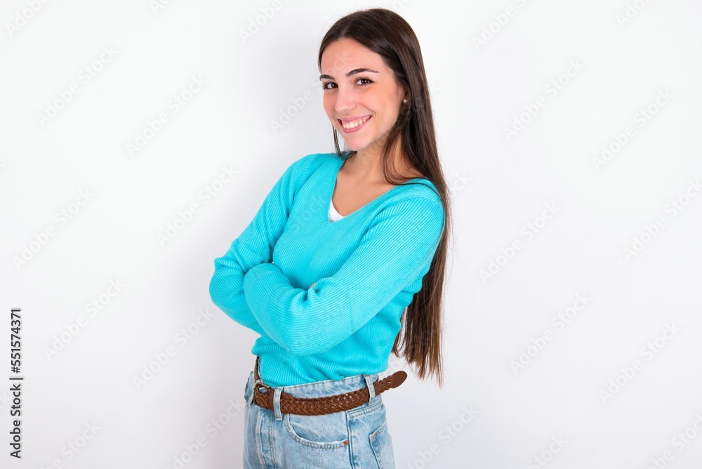 Portrait of Young caucasian woman wearing blue sweater over white background standing with folded arms and smiling Portrait of Young caucasian woman wearing blue sweater over white background standing with folded arms and smiling