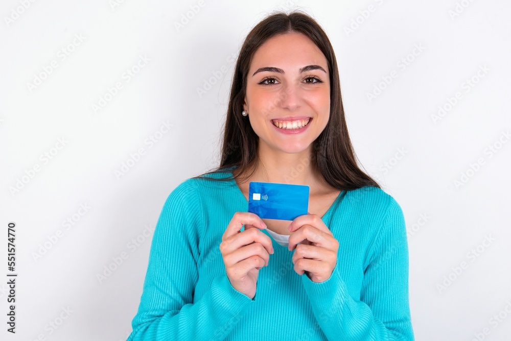 Photo of Young caucasian woman wearing blue sweater over white background positive smile hold credit card income salary Photo of Young caucasian woman wearing blue sweater over white background positive smile hold credit card income salary