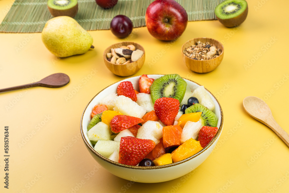 Fresh fruit salad in a bowl. Multicolored and tropical fruits. Pineapple, mango, grape, strawberry, papaya, melon, kiwi. Additional with chestnuts and granola. Selective focus Fresh fruit salad in a bowl. Multicolored and tropical fruits. Pineapple, mango, grape, strawberry, papaya, melon, kiwi. Additional with chestnuts and granola. Selective focus