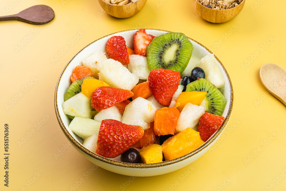 Fresh fruit salad in a bowl. Multicolored and tropical fruits. Pineapple, mango, grape, strawberry, papaya, melon, kiwi. Additional with chestnuts and granola. Selective focus Fresh fruit salad in a bowl. Multicolored and tropical fruits. Pineapple, mango, grape, strawberry, papaya, melon, kiwi. Additional with chestnuts and granola. Selective focus
