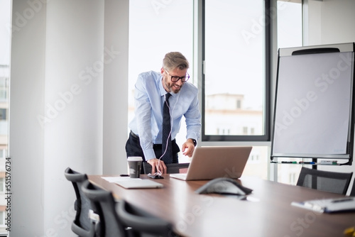 Professional businessman using cellphone and laptop while sitting at the office