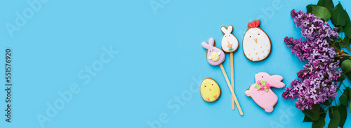 Easter gingerbread with icing, bunny, chicken, egg, seasonal flowers on blue backdround. Happy festive floral concept, glazed cookie figures composition. Flat lay, top view, place for text, banner