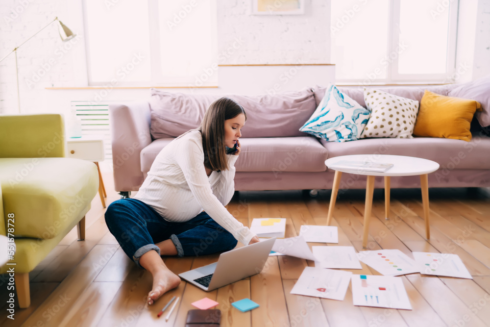 Pregnant woman doing paperwork while talking on smartphone at home Pregnant woman doing paperwork while talking on smartphone at home