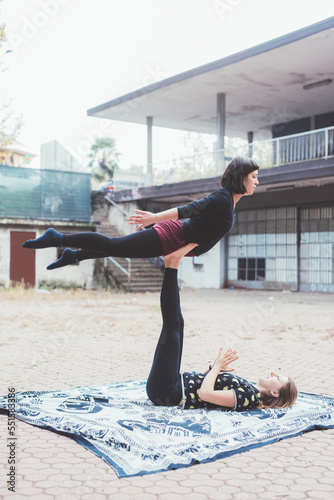 Healthy acrobatic couple woman doing flexible yoga asana exercise practicing