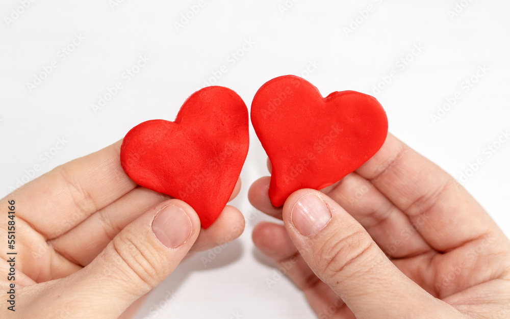 Fototapeta premium plasticine clay red color heart shape in kid woman mother son hands palm.diy do it yourself activities valentines love february 14th day back to school creative.modeling clay imagination development
