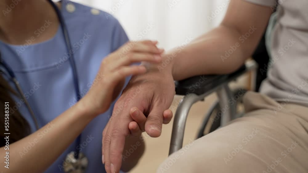 closeup with selective focus of hands of nursing aide holding and patting winkled hand of a patient on wheelchair. Domiciliary care for sick elderly people concept closeup with selective focus of hands of nursing aide holding and patting winkled hand of a patient on wheelchair. Domiciliary care for sick elderly people concept