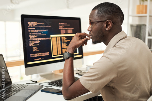 Pensive software engineer reading programming code on laptop screen photo