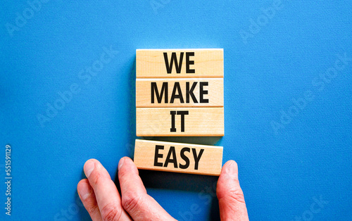 We make it easy symbol. Concept words We make it easy on wooden cubes. Beautiful blue table blue background. Businessman hand. Business motivational we make it easy concept. Copy space. photo