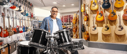 Casual mature man trying drums in a music shop