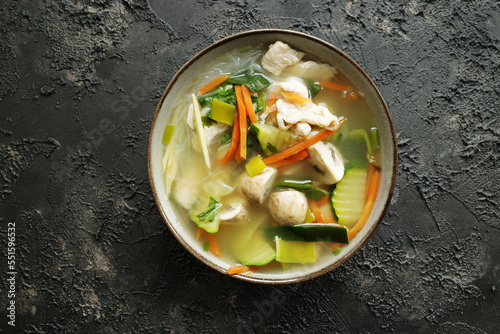 Chicken soup with veggies and glass noodles on a dark textured background