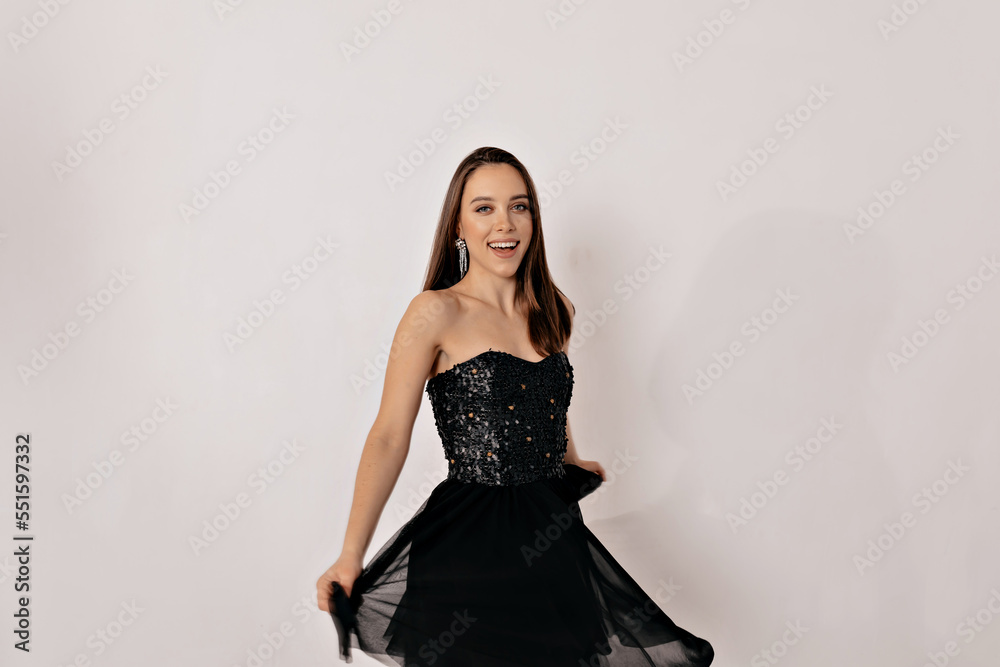 Happy smiling pretty girl with short dark hair wearing black bright dress and bright jewelry dancing, celebrating, having fun Happy smiling pretty girl with short dark hair wearing black bright dress and bright jewelry dancing, celebrating, having fun