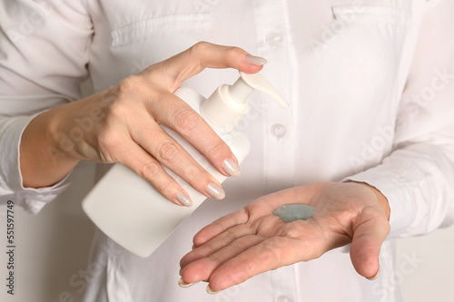 Female hands in a white shirt hold a white plastic dispenser.