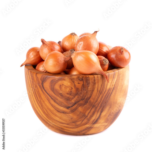Brown mini onions in wooden bowl, isolated on a white background. Raw onion bulbs, for cultivation. French onion.
