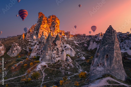 Ancient town of Uchisar castle with hot air balloons at sunset Goreme national park, Cappadocia Turkey, aerial top view