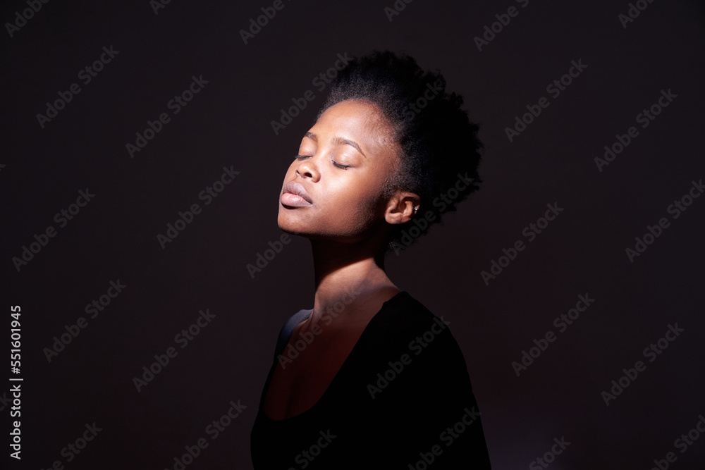 A black woman showing emotions. A woman with an emotional expression and closed eyes on a black background with a ray of light on her face. With space to copy. High quality photo A black woman showing emotions. A woman with an emotional expression and closed eyes on a black background with a ray of light on her face. With space to copy. High quality photo
