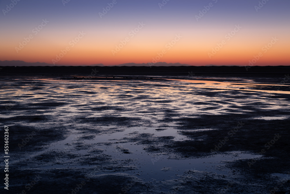 Colorful sunrise sky reflected in many puddles on the beach at low tide, Dahab, Egypt
