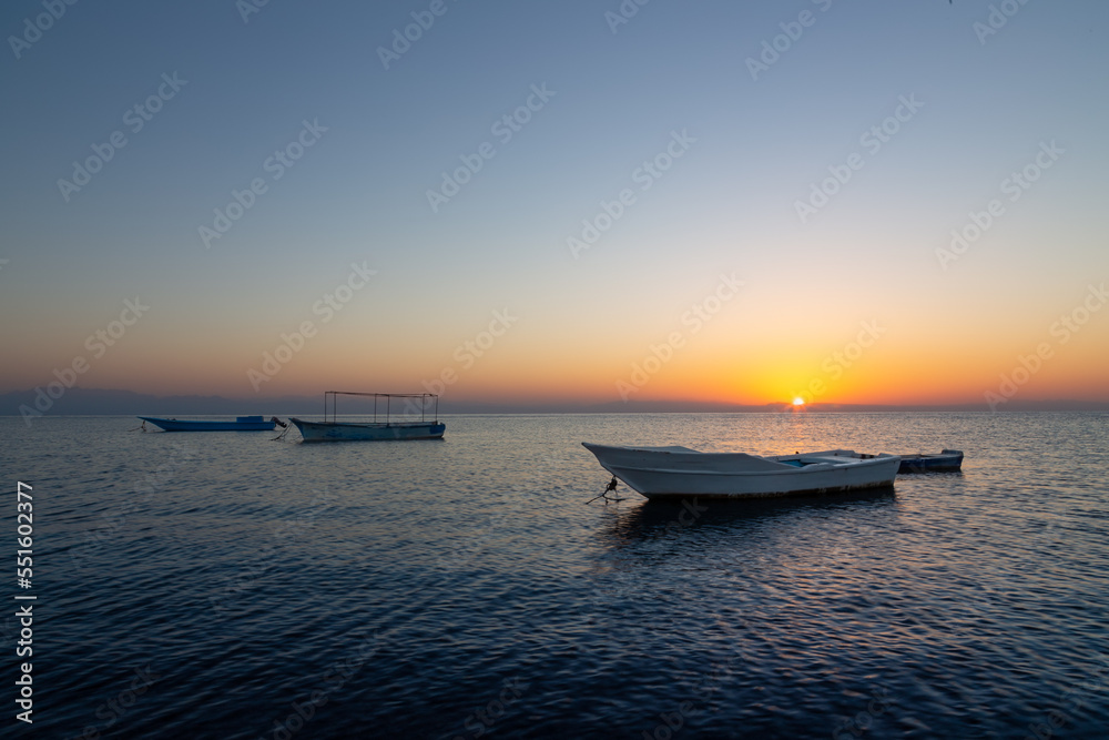 Colorful sunrise seascape with a fisherman boat in the foreground, Dahab, Sinai, Egypt