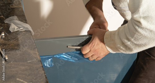  Worker fixing kitchen cabinet using screwdriver.