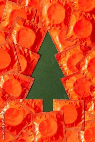 Creative composition with many red packs of condoms on deep green background. Cool xmas tree shape negative space.