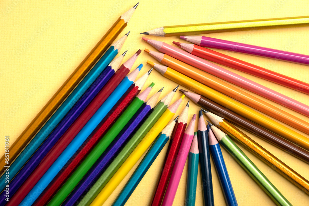 There are many different colored pencils scattered on a colored background. There are many different colored pencils scattered on a colored background.