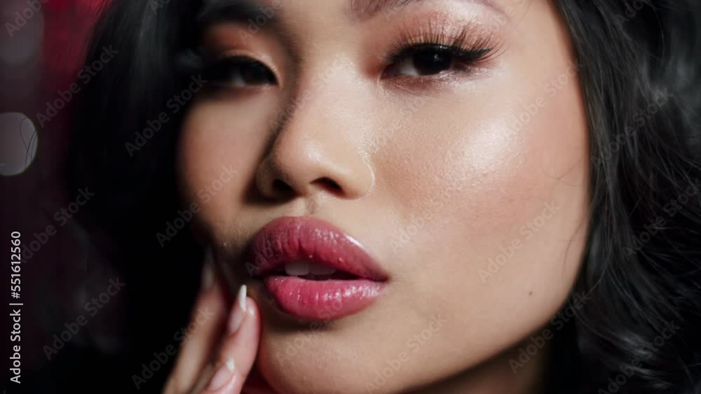 Alluring glamour asian woman with sensual look posing to a camera over red shiny background. Close up. Alluring glamour asian woman with sensual look posing to a camera over red shiny background. Close up.