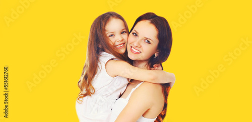 Portrait of happy smiling mother with daughter child on yellow background