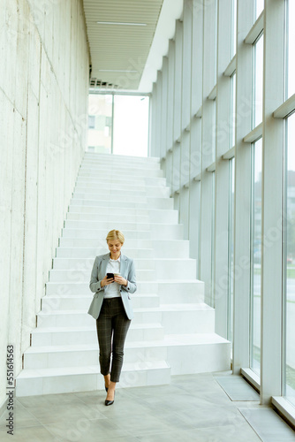 Businesswoman using mobile phone on modern office hallway