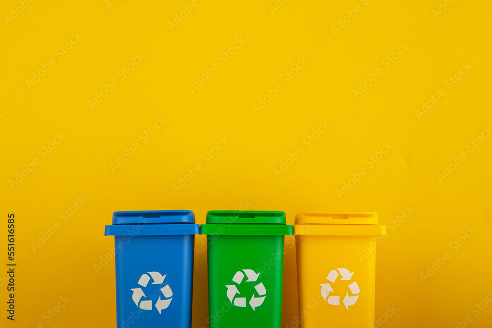 Plastic yellow, green and blue trash can on yellow background Plastic yellow, green and blue trash can on yellow background