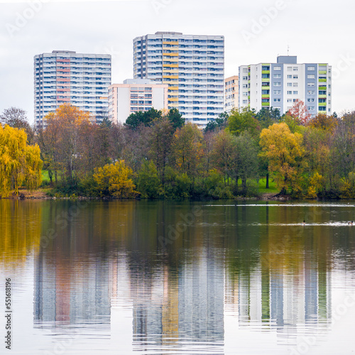 Colorful autumn trees and city buildings symmetrical reflected in lake