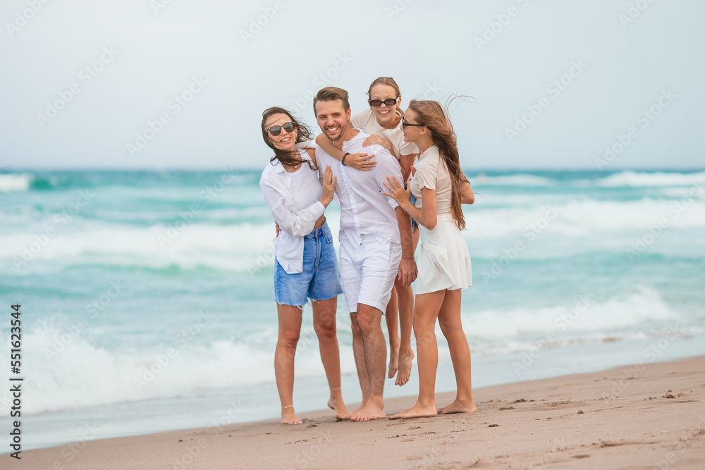 Family of young parent and two kids smiling and enjoy time together on the beach vacation Family of young parent and two kids smiling and enjoy time together on the beach vacation