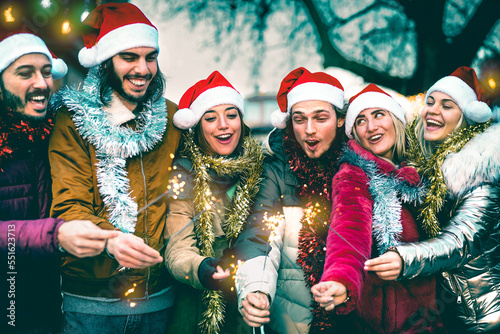 Young people group cheering with sparklers at Christmas time - Cold winter life style concept with trendy happy friends wearing red santa hats having fun holiday together outside - Azure vivid filter