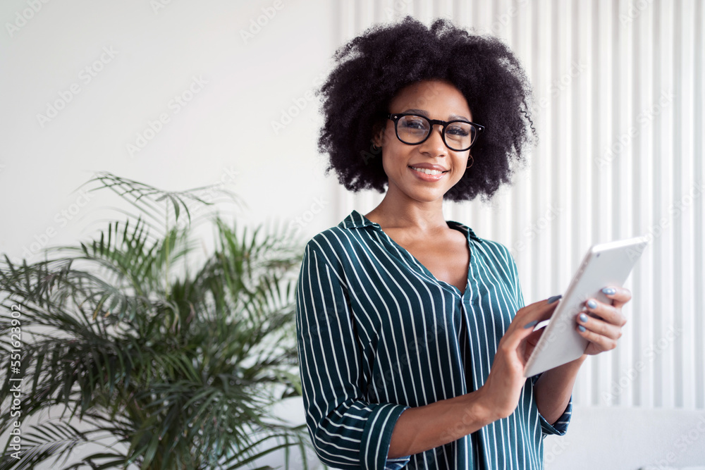 A happy woman with glasses uses a tablet to make a report online. Manager in business glasses for computer. A happy woman with glasses uses a tablet to make a report online. Manager in business glasses for computer.
