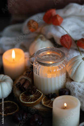 Autumn home composition with aromatic candle  dry citrus  cinnamon  anise. Aromatherapy on a grey fall morning  atmosphere of cosiness and relax. Wooden background close up