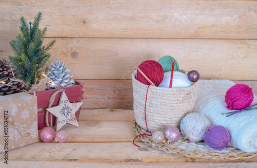 woolen colorful balls with crochet hooks in a wooden box, with christmas balls on wooden ground
