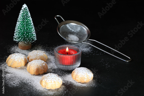 Cookies sprinkled with powdered sugar, red candle,small green christmas tree, colander