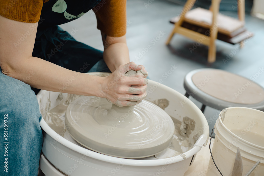 Closeup of potter hands working on pottery wheel in ceramic studio with clay hands side view with pottery wheel in motion Closeup of potter hands working on pottery wheel in ceramic studio with clay hands side view with pottery wheel in motion