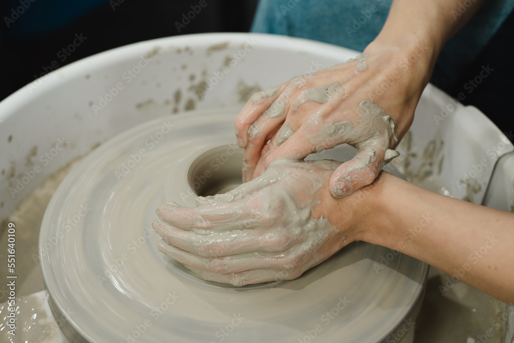Closeup of potter hands working on pottery wheel in ceramic studio with clay hands side view with pottery wheel in motion