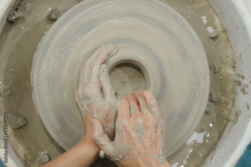 Closeup of potter hands working on pottery wheel in ceramic studio with clay hands top birds eye view with pottery wheel in motion
