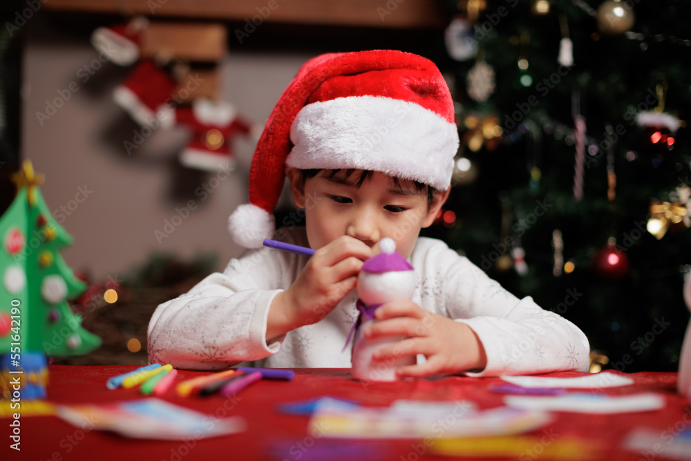 young girl wearing santa hat was making Christmas craft at home young girl wearing santa hat was making Christmas craft at home