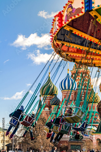 Children ride a carousel in Red Square in spring with St. Basil's Cathedral in the background. Joy. Childhood. Moscow, Russia.