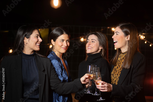 group of young women toasting with champagne glasses with elegant dresses