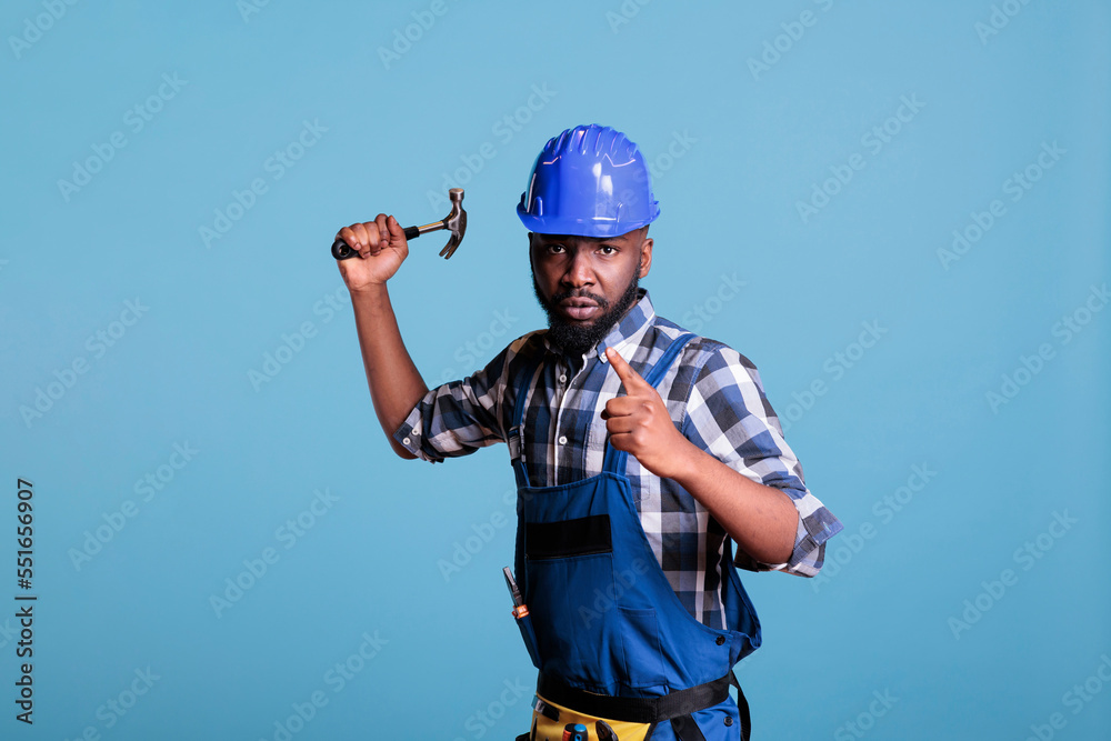 Aggressive and disruptive construction worker raising hammer towards