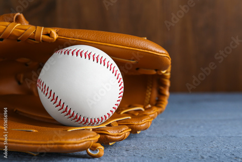 Leather baseball glove with ball on grey wooden table, closeup. Space for text